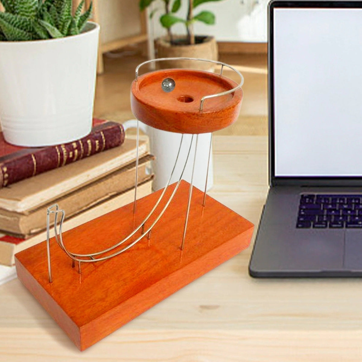 Kinetische Kunstskulptur neben Laptop und Pflanze